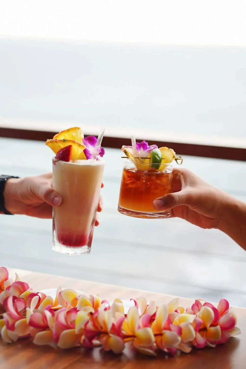 Two guests toasting cocktails over the water